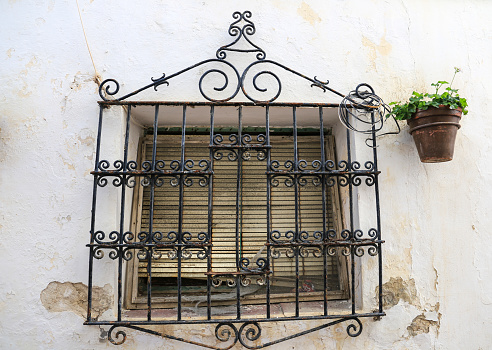 Old window with iron grid decorated with red geranium flowers