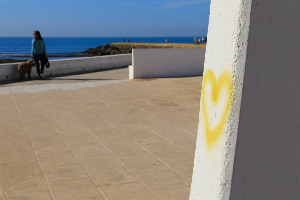 Yellow heart drawn on wall on Playa de la Costilla beach and promenade in Rota city, Cadiz, on a sunny day