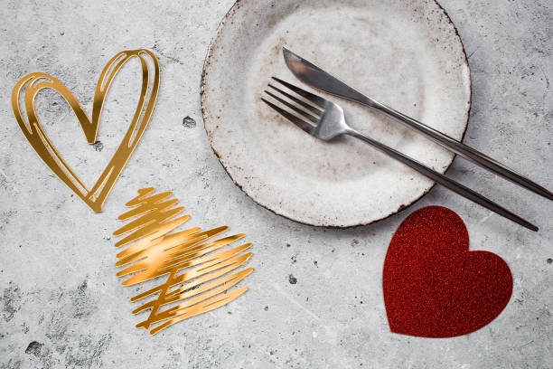 istock The banner. Table setting. Stylish ceramic plate and gold, red hearts on a concrete background. The concept of celebrating Valentine's Day for cafes and restaurants. 1979565277