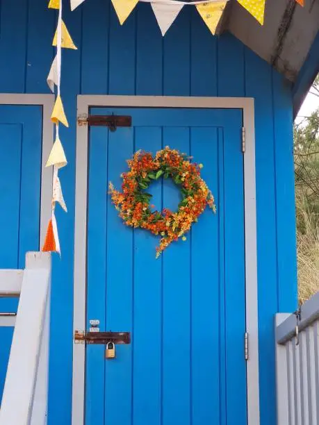 blue beach hut door with a wreath and bunting