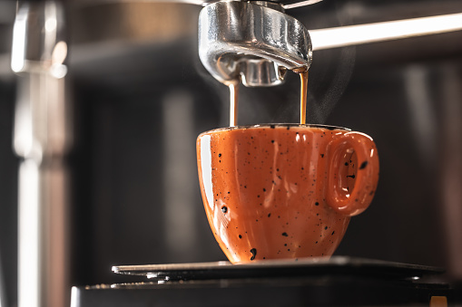 The coffee machine makes coffee into an orange cup.