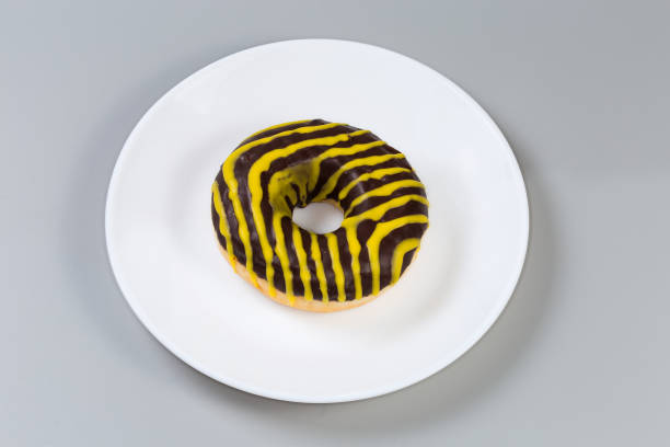 istock Doughnut with chocolate and yellow glaze on a white dish 1979628302