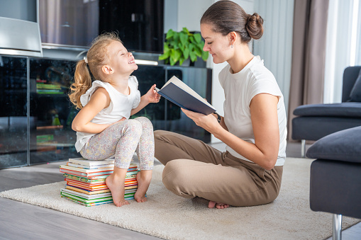 Young mother is reading a book to her cute daughter. High quality photo