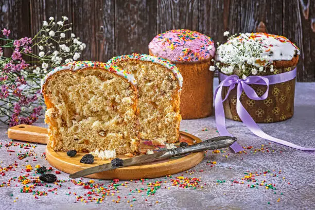 A cut Eastercake on a tray is a traditional Ukrainian holiday baking. Knife, raisins, Easter eggs, sprinkles as decoration. Festive composition.