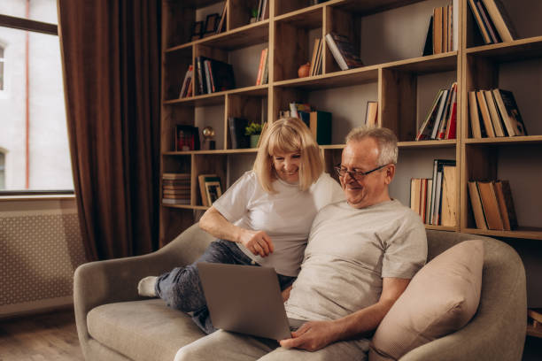 istock Couple senior using computer laptop on sofa at home for online shopping, surfing internet. 1979665867