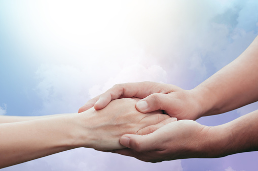 Close up of two people holding hand together over blurred sky background,Business man and woman shaking hands,helping hand  and world peace, team work unity concept with copy space for your text