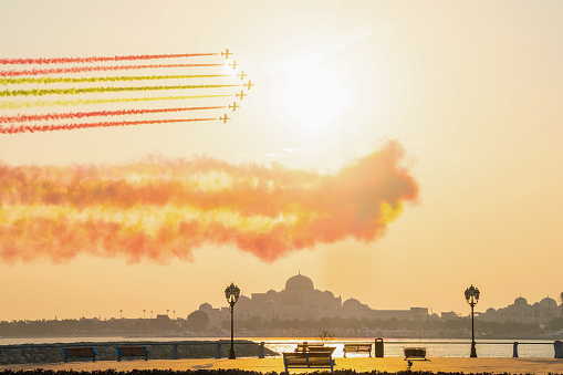 Abu Dhabi, UAE - Desember 4, 2023: Air show with seven jet planes flying over presidential palace in Abu Dhabi paint the sky with flag colour in sunset. High quality photo. High quality photo