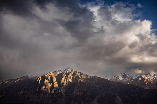 Last beam of light at sunset hitting the mountain peak, in  Nubra Valley surrounded by mountain peaks of the greater Himalayas.