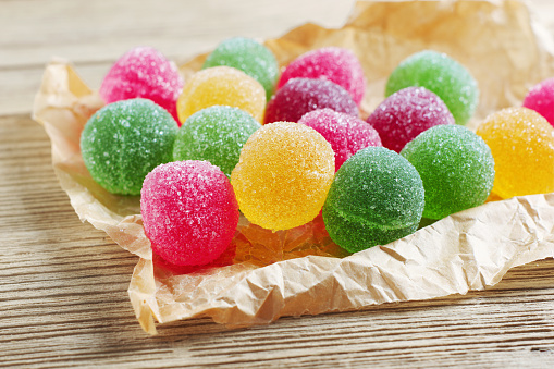 Marmalade candy balls on crumpled paper on old wooden background