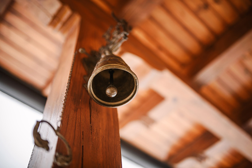 Close up of a brass bell with an ornate chime lit up by lighting in the background