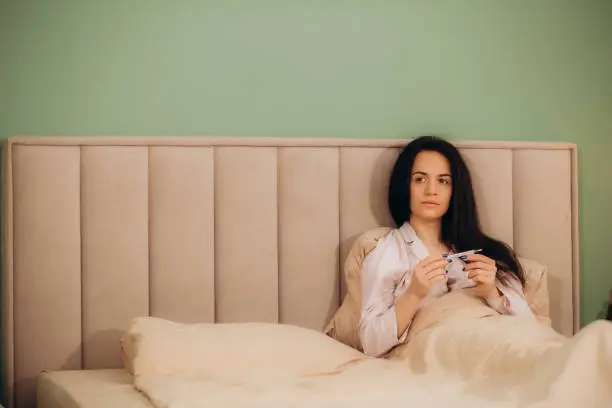 Woman measuring temperature her body on the bed. person got fever lying on the sofa.