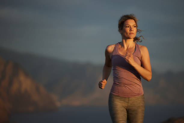Determined athletic woman jogging during sports training on a cliff. Copy space.