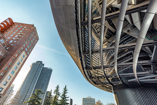 Madrid, Spain. Low angle view of part of the covering structure of the new facade of the Santiago Bernabéu Stadium surrounded by residential and commercial buildings.