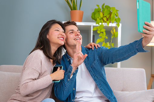 Young smiling multiracial friends taking a selfie in living room. Concepts of youth, people's lifestyle, diversity, urban life