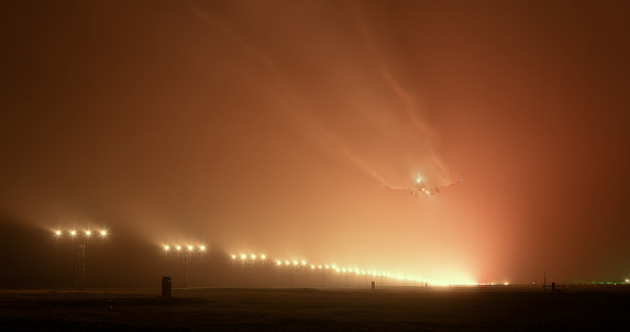 Passenger plane landed at the airport in foggy night weather. Shot from behind, the thrilling scene is full of wingtip vortices during landing.