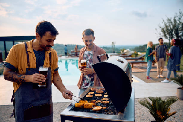istock Young man making barbecue while having pool party with friends. 1979815518