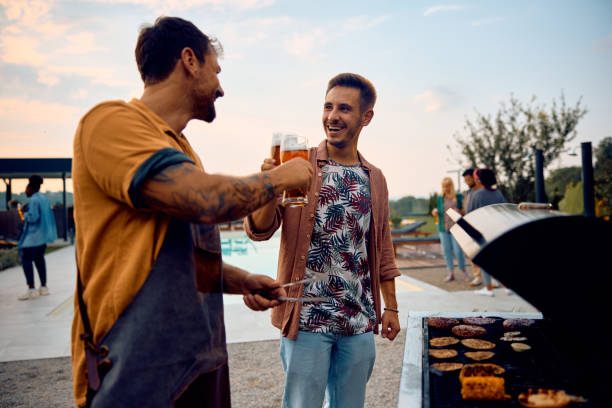 istock Happy men toasting with beer while making barbecue outdoors. 1979815525