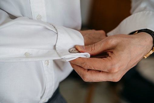 A man in a white shirt adjusting wrist