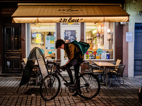 Strasbourg, France - Mar 15, 2018: Front view of the 231 East burger restaurant and Deliveroo e-food driver on his bike