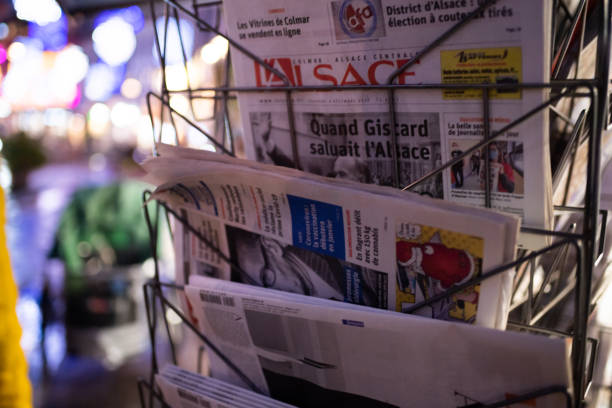 Strasbourg, France - Dec 4, 2020: French newspapers at press kiosk with defocused city background at dusk