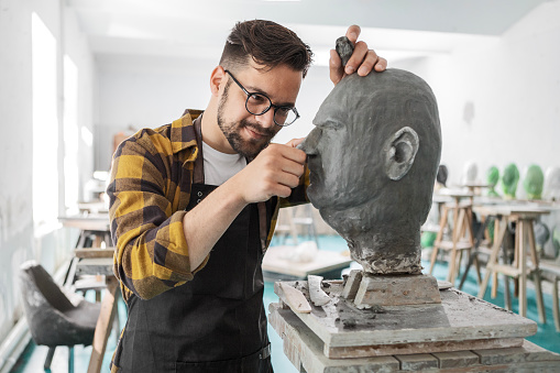 Young man sculpting head out of clay