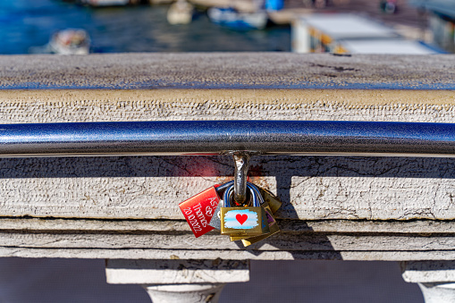 Close-up of locks with names and heart fixed at railing of Scalzi Bridge at the old town of Italian City of Venice on a sunny summer day. Photo taken August 7th, 2023, Venice, Italy.