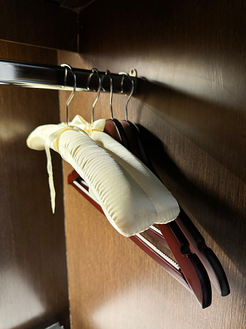 Stock photo showing close-up view of an empty hotel closet with wooden coat hangers on a metal rail.