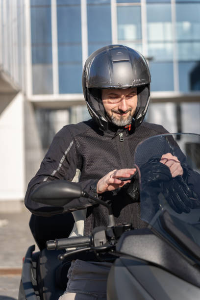 istock Caucasian biker putting on gloves, while sitting on a motorcycle with an helmet on 1979885421