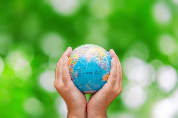 istock Man holding global earth globe in hands.Green leaves blurred background.Copy space.Environment concept. 1979887620