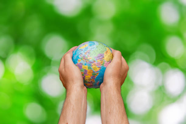 istock Man holding global earth globe in hands.Green leaves blurred background.Copy space.Environment concept. 1979887622