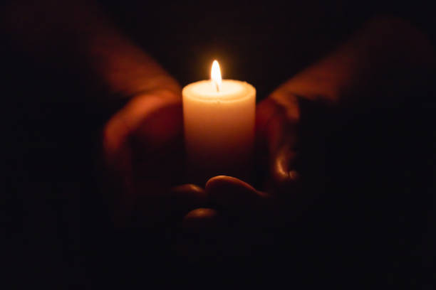 istock Hands holding burning candle in dark like a heart.Selective focus,black background. 1979892379