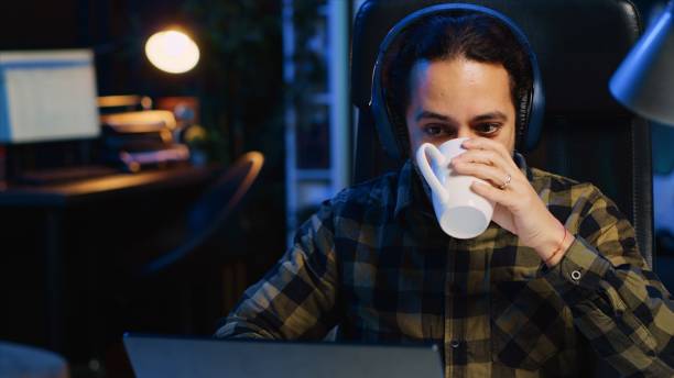 istock Happy man drinking coffee and writing emails at home office desk 1979898240