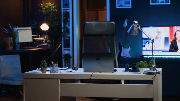 istock Office desk filled with business items in empty home interior with TV left open 1979901427