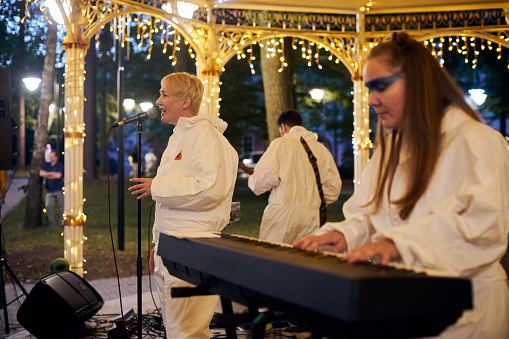 Svetlogorsk, Russia - 13.08.2023 - Local pop rock music band performs in gazebo of city public park, side view of keyboardist to energetic outdoor performance in evening lights of park