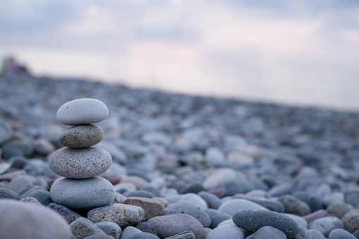Stacked stones on a beach against the backdrop of the sea. Large tower of stones background of small pebbles. Serenity and calmness. Recreation concept