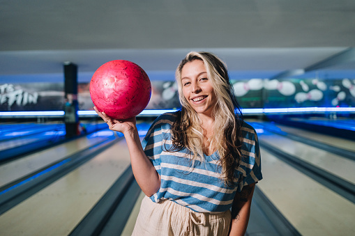 Portrait of a young woman holding a bowling ball at a bowling club