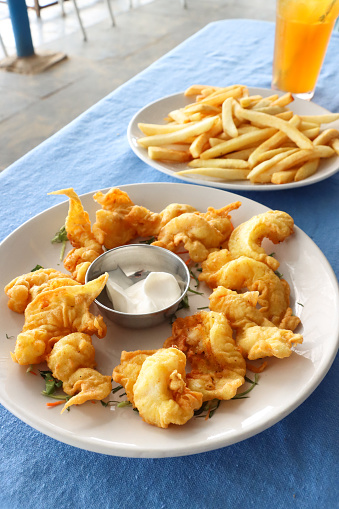 Stock photo showing close-up, elevated view of an appertiser (starter) of prawn tempura served with metal bowl of mayonnaise. Tempura is deep-fried pieces of prawn coated in batter.