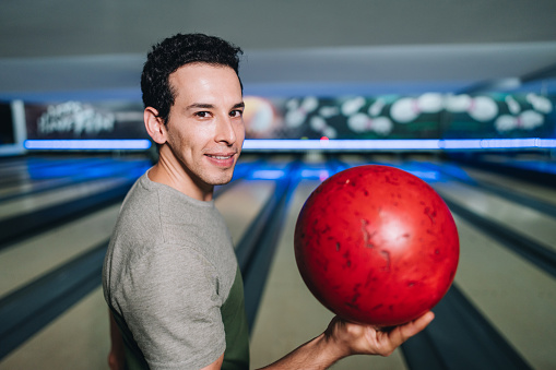 Portrait of a mid adult man holding a bowling ball at a bowling club