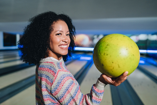 Portrait of a young woman holding a bowling ball at a bowling club