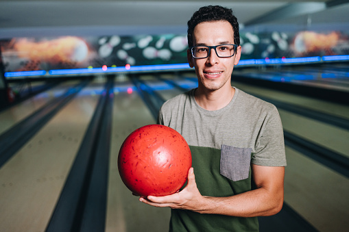 Portrait of a mid adult man holding a bowling ball at a bowling club