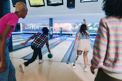 Friends throwing a bowling ball at a bowling club - including a person with a prosthesis leg