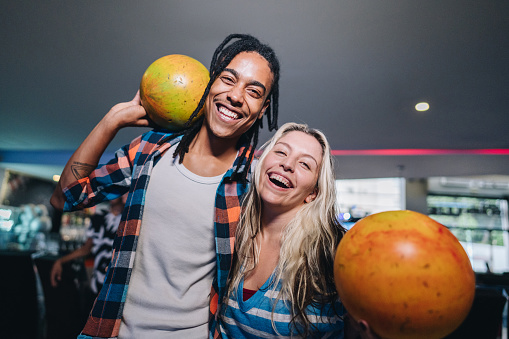 Portrait of friends holding bowling balls at a bowling club