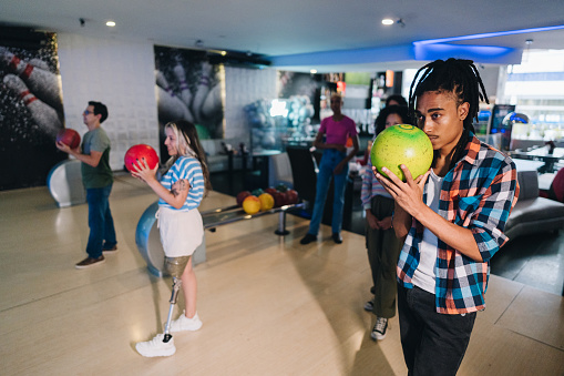 Young man preparing to throw a bowling ball at a bowling club with friends