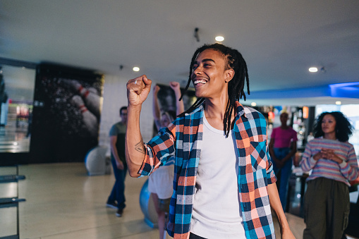 Young man bowling at a bowling club with friends