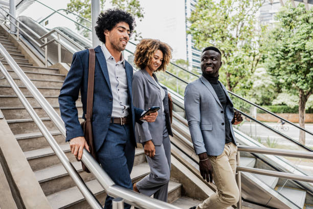 istock Coworkers talking while moving down the stairs outdoors 1979963883
