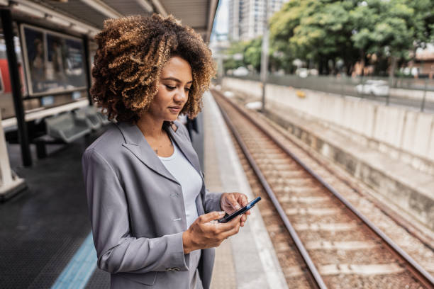 istock Businesswoman using the mobile phone while waiting for the train on the platform 1979966572