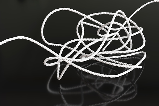 A tangle of white rope on reflective black surface. Illustration of the concept of brain cloud and confusion