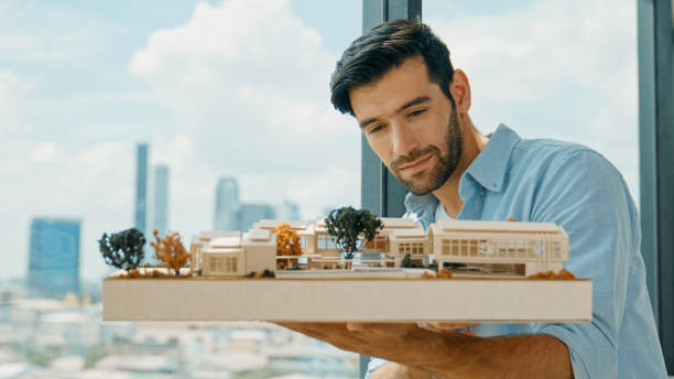 istock Businessman holding house model while checking house construction. Tracery 1980021678