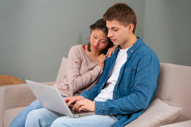 istock Happy multiethnic man and woman have fun browsing internet on laptop. Technology concept. 1980033146