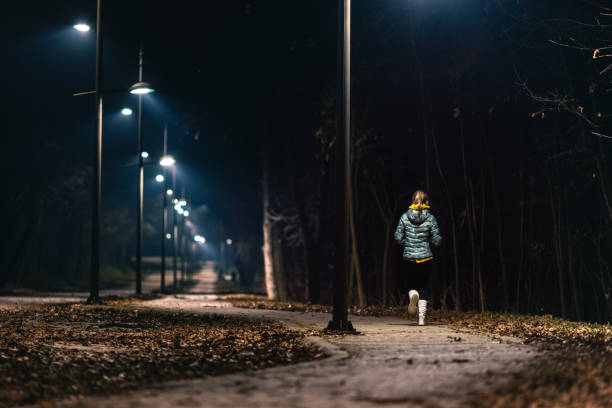 istock Young woman jogging in park at night 1980045419